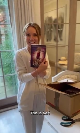Geri Horner holds up copy of her book in her lavish home