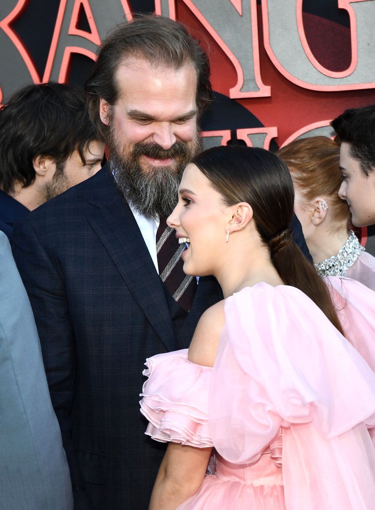 David Harbour in navy suit and Millie Bobby Brown in pink dress at season 3 premiere