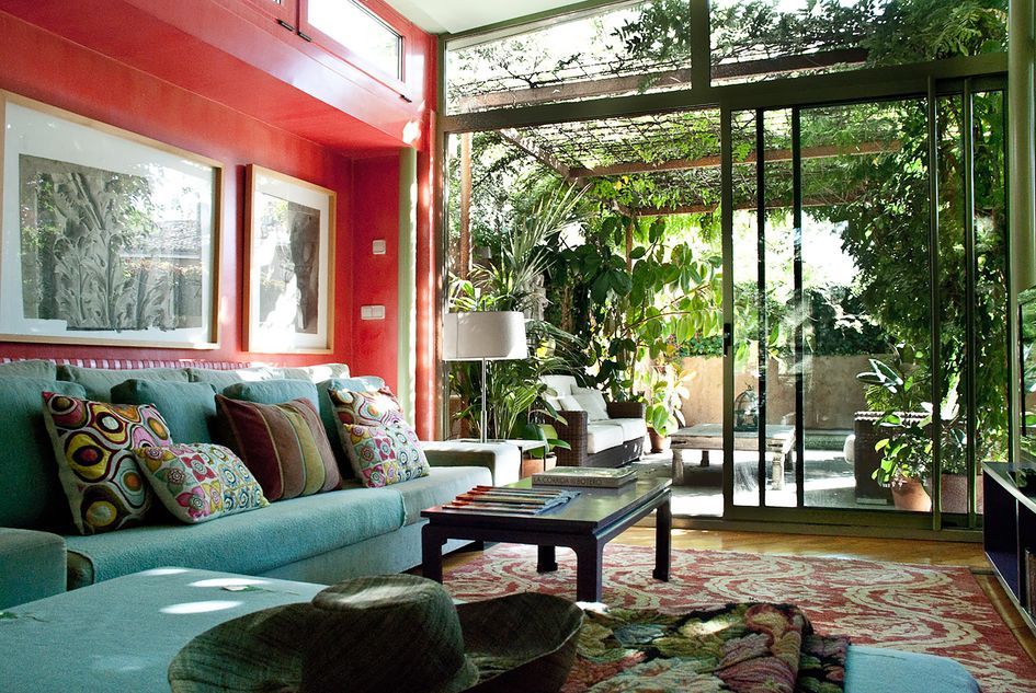 Vibrant living room designed by Pía López-Izquierdo Botín featuring a bold red accent wall and a large seafoam green sectional sofa