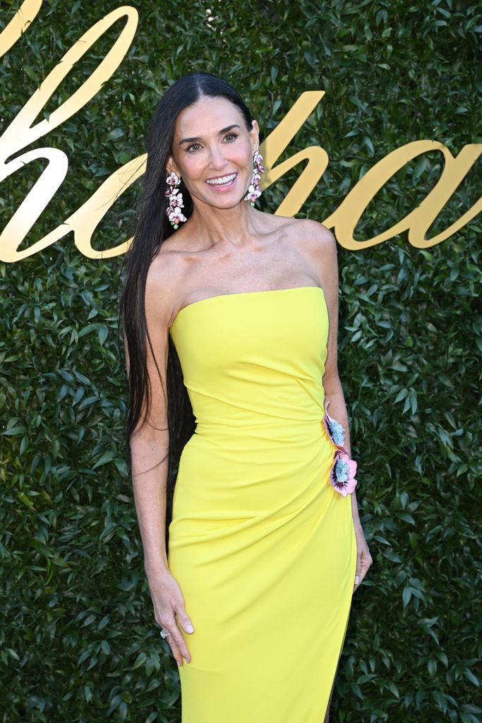 Demi Moore smiling in yellow dress and statement earrings