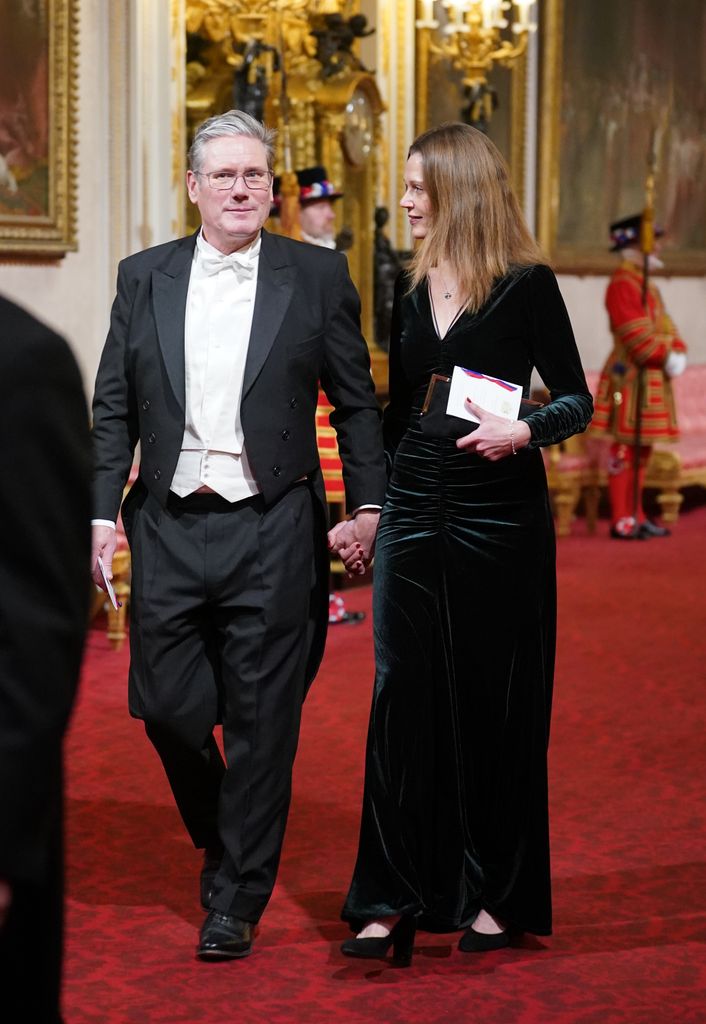 Victoria Starmer in a velvet evening dress walking with Keir