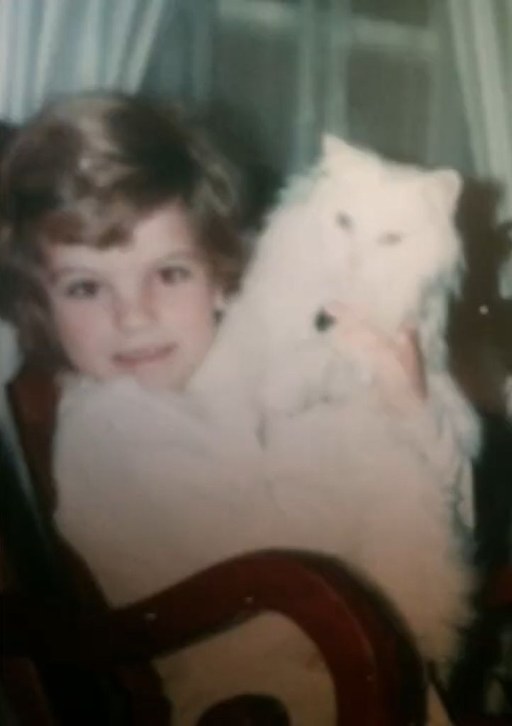 Pauley Perrette as a young girl sitting with a cat