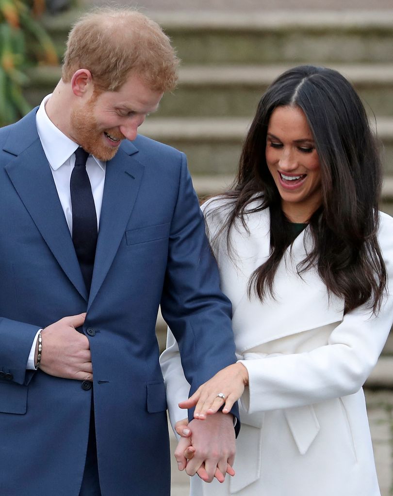 Britain's Prince Harry stands with his fiancÃ©e US actress Meghan Markle as she shows off her engagement ring whilst they pose for a photograph in the Sunken Garden at Kensington Palace in west London on November 27, 2017, following the announcement of their engagement. Britain's Prince Harry will marry his US actress girlfriend Meghan Markle early next year after the couple became engaged earlier this month, Clarence House announced on Monday. (Photo by Daniel LEAL / AFP) (Photo by DANIEL LEAL/AFP via Getty Images)