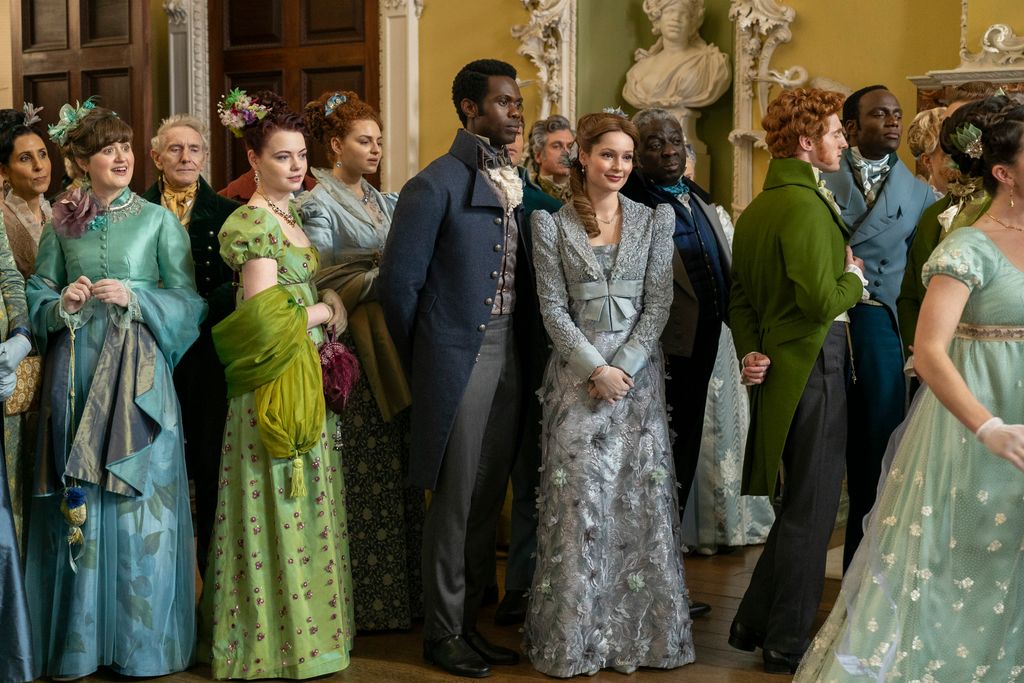 group of people in period clothing standing in ballroom
