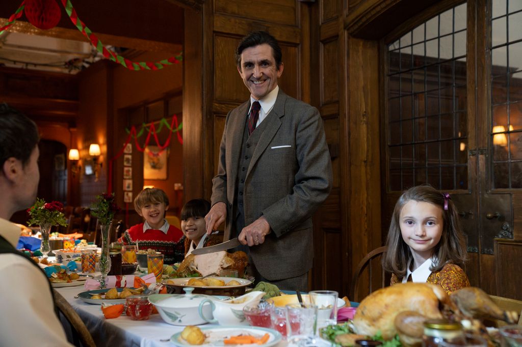 Man in grey suit carving turkey at Christmas