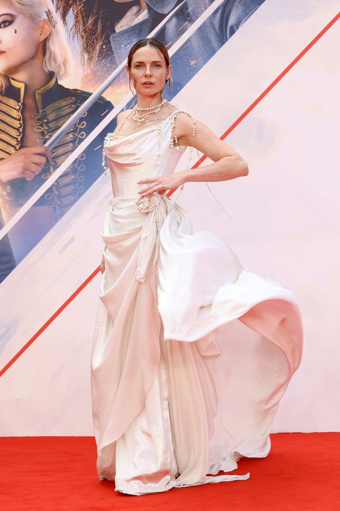 Rebecca channels ethereal goddess vibes in a pearl-draped, flowing white gown with soft draping details at a red carpet.