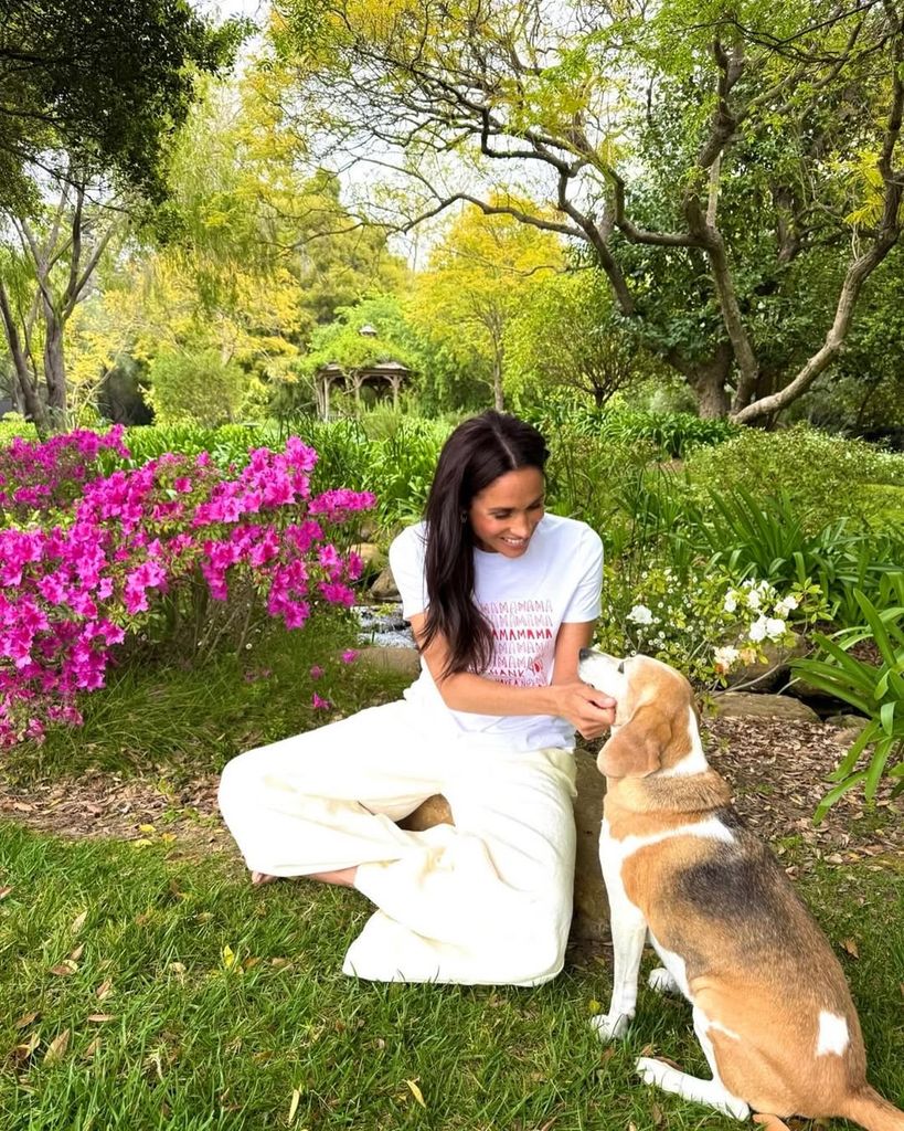 Meghan sat cross legged petting her dog in her garden