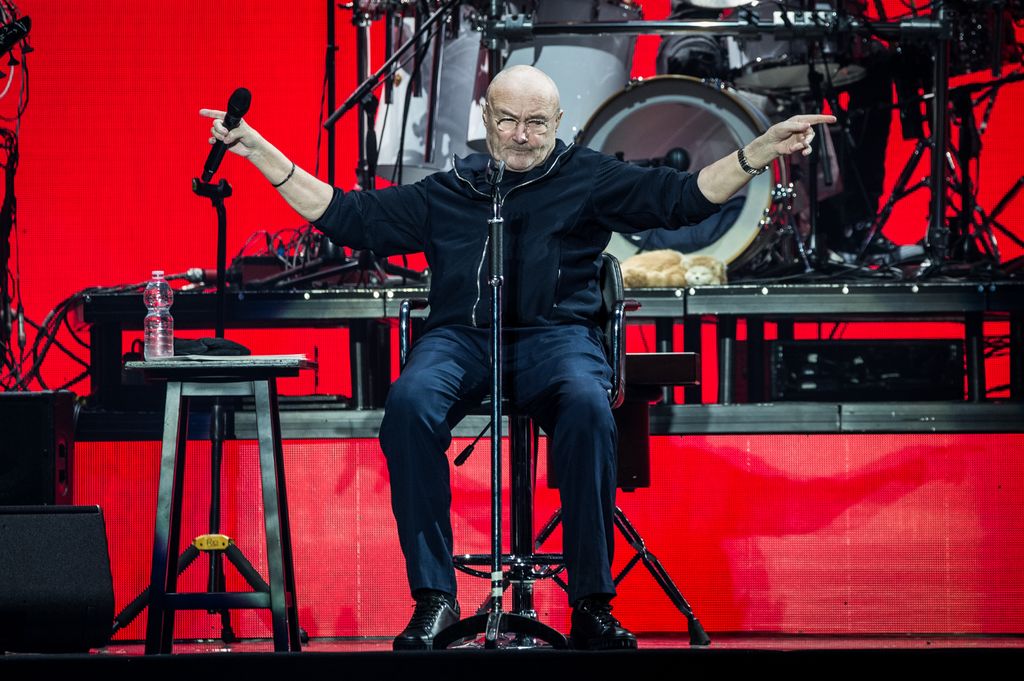 Phil Collins sitting in a chair while performing