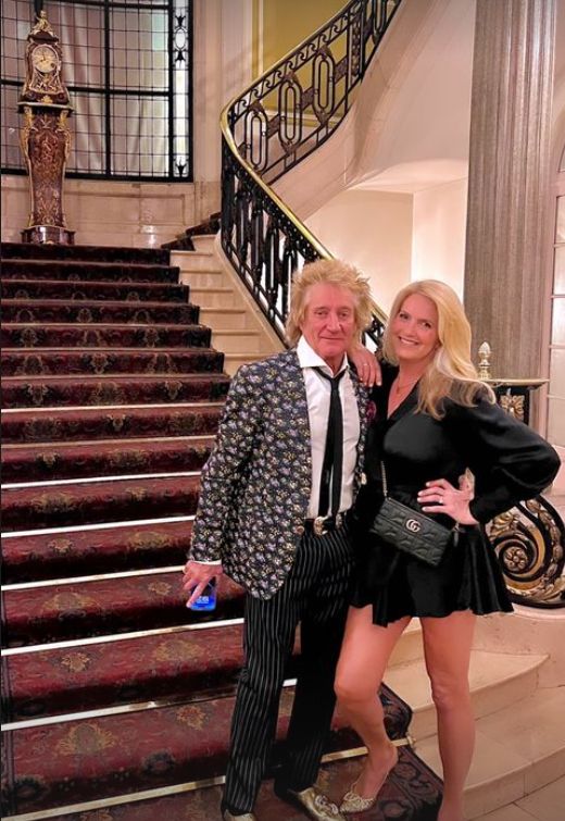 Rod Stewart standing with Penny Lancaster on a set of stairs