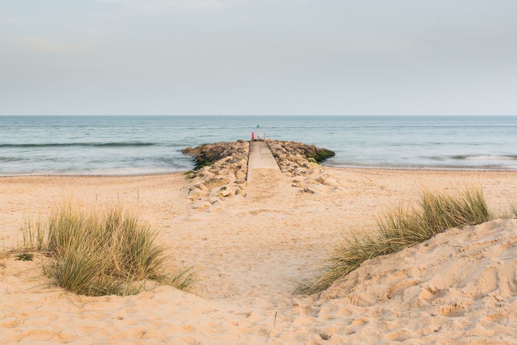Vue de derrière les dunes de sable en regardant vers un groyne rocheux sur une plage dans des bancs de sable, Dorset