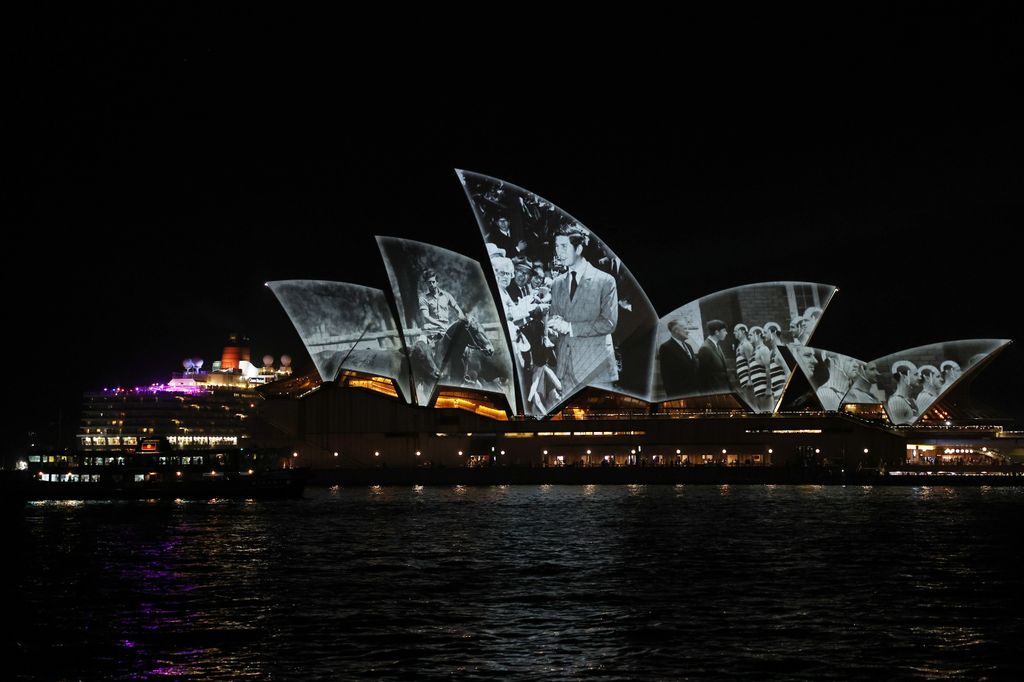 The Queen Elizabeth sails past as the Sydney Opera House shells are illuminated with a Royal projection to officially welcome King Charles III and Queen Camilla  