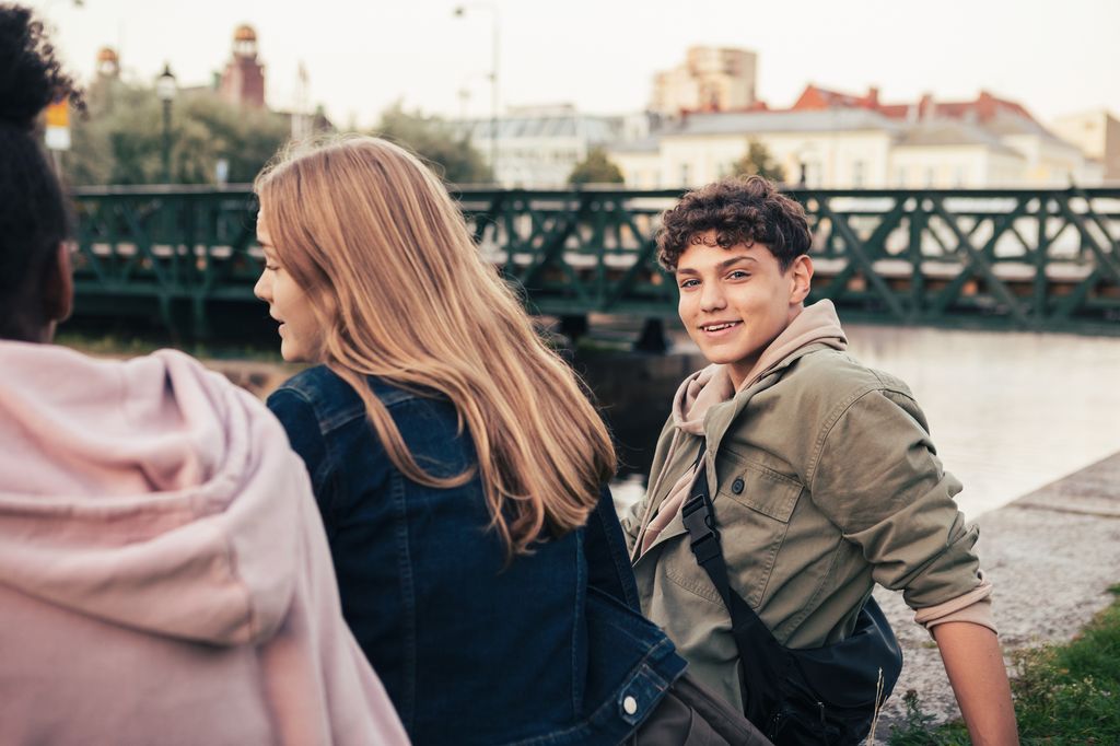 Teen boy and girls sitting by river