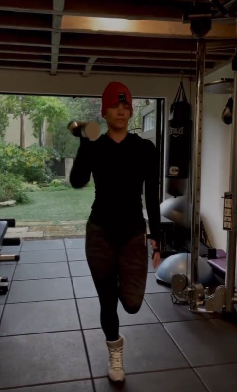 Halle Berry in black workout gear with a dumbbell