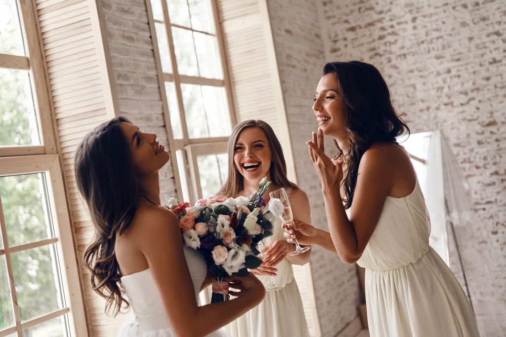A bride laughing with two bridesmaids