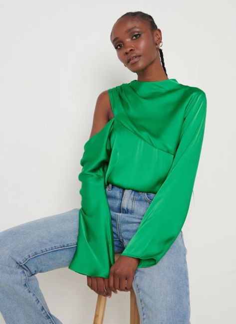 a model wears the same bright green satin asymmetric blouse as amanda and they pose in a seated position wearing jeans