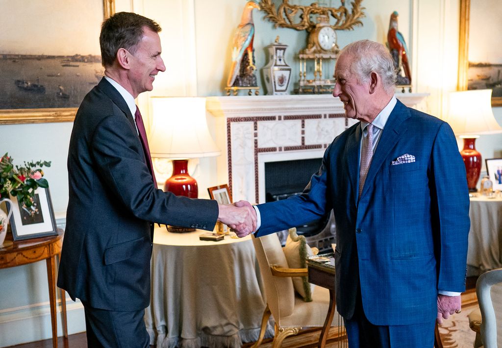 Britain's King Charles III (R) shakes hands with Britain's Chancellor of the Exchequer Jeremy Hunt, 