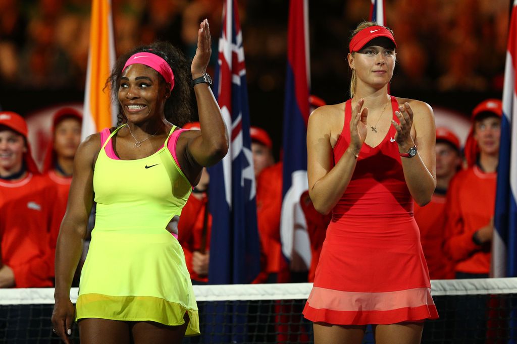 Two women stand on a podium waiting to be awarded trophies