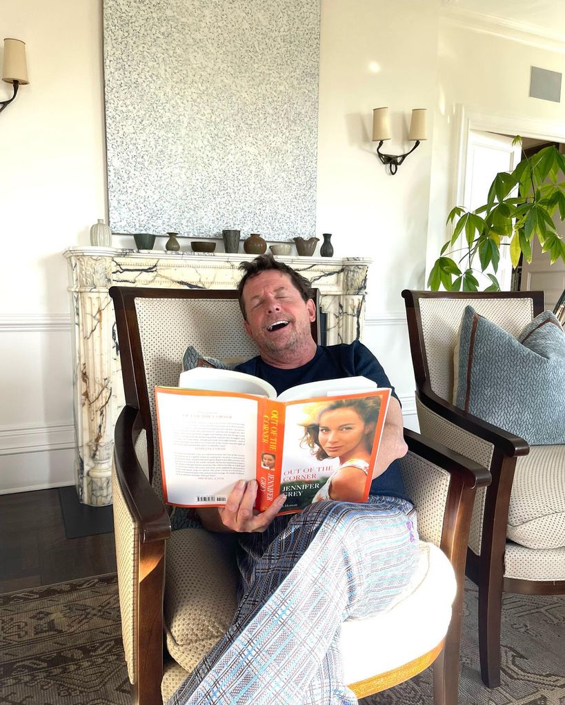 Michael j fox reading book in chair in living room