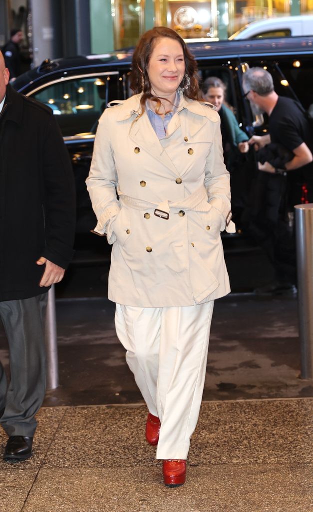 Elizabeth Ann Hanks walking in New York wearing a cream trench coat