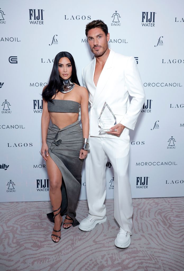 Kim Kardashian in grey dress posing with her hairstylist Chris Appleton in white suit