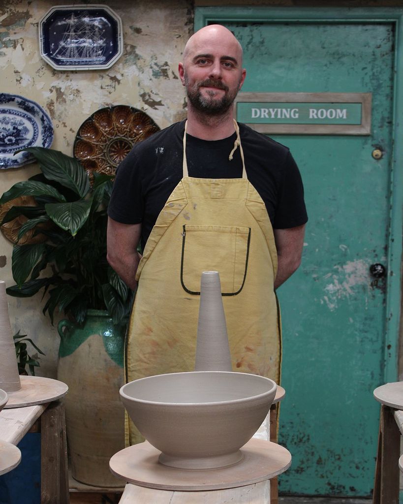 Man in apron in front of clay bowl