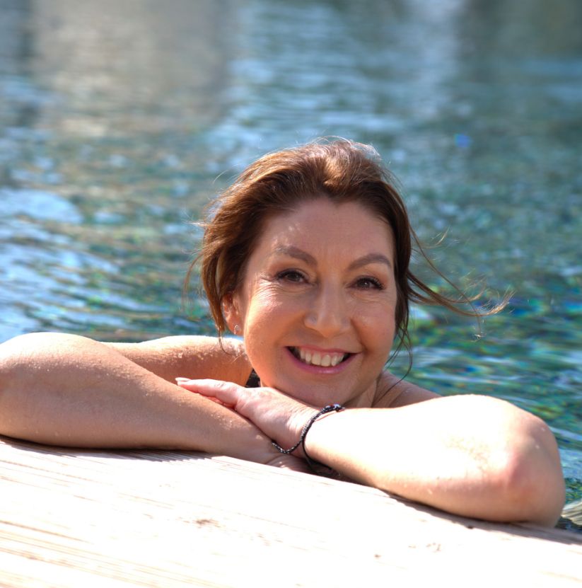Jane McDonald on the side of a swimming pool in black one-piece