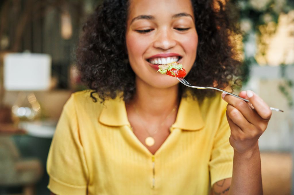 woman in yellow top looking at food on fork