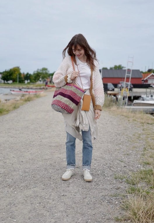 Lily Collins walking by a small port holding a bag