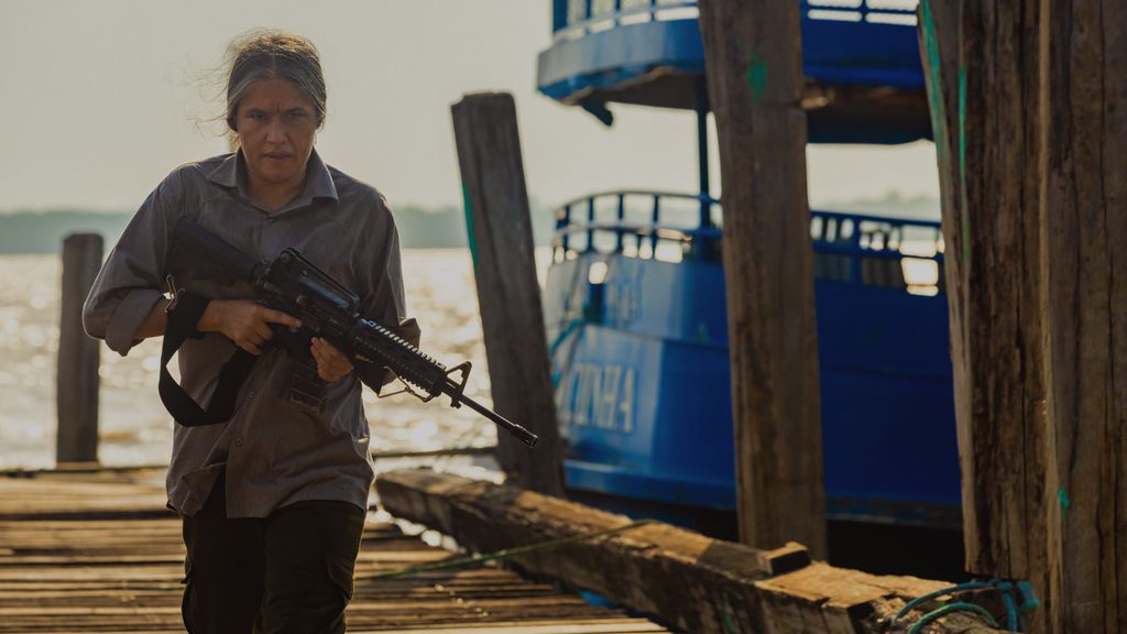 older woman holding gun walking down dock