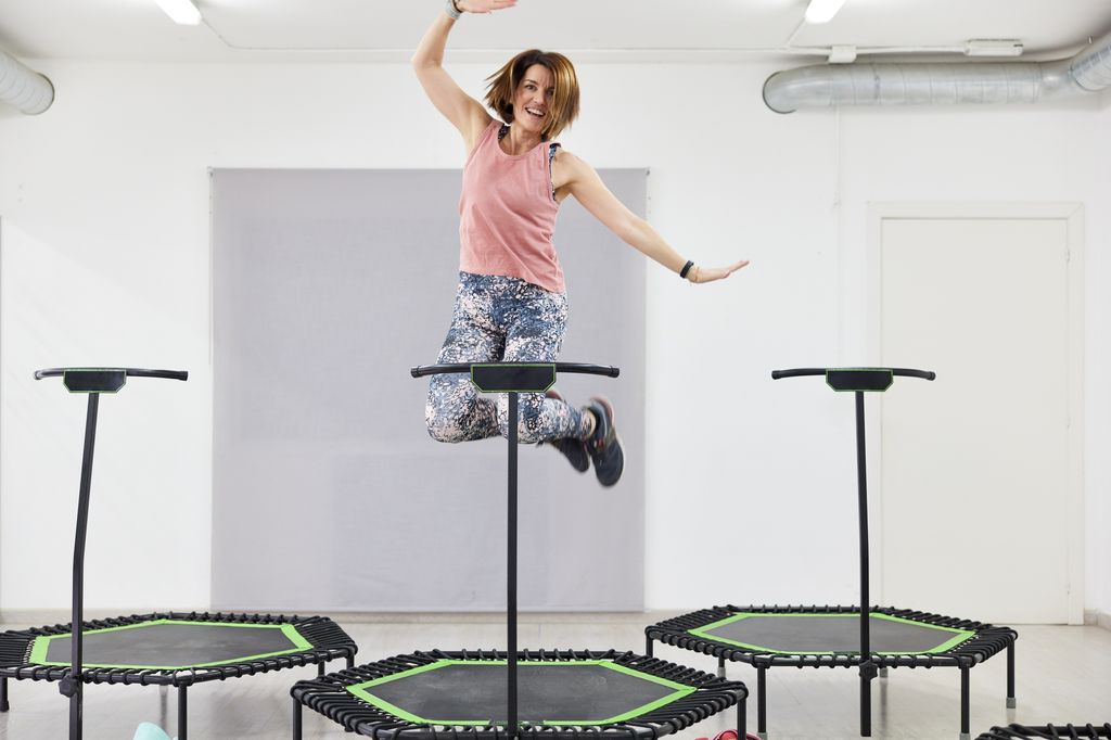 A woman jumping and making gestures in a fitness trampoline.