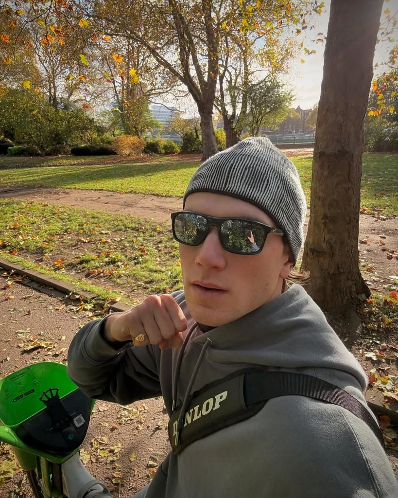 Jack Draper in a beanie hat and glasses while riding a lime bike through London