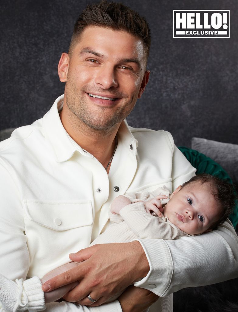 Aljaz Skorjanec wears white polo neck as he poses with baby Lyra