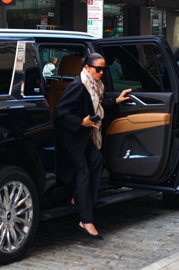 Meghan Markle stepping out of a car in a Hermes scarf and black outfit