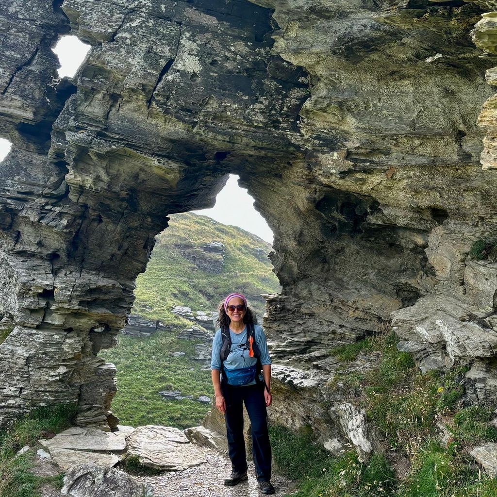 woman standing under a rock formation 