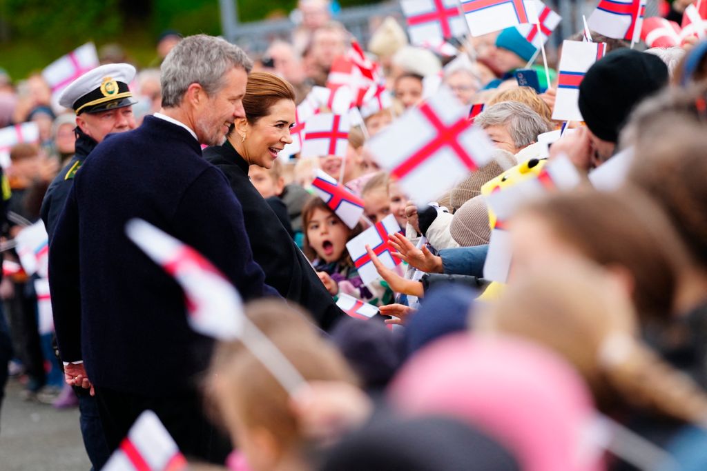 Danish Queen Mary and King Frederik X greet wellwishers as they arrive with the Royal Yacht at Bursatangi in Torshavn