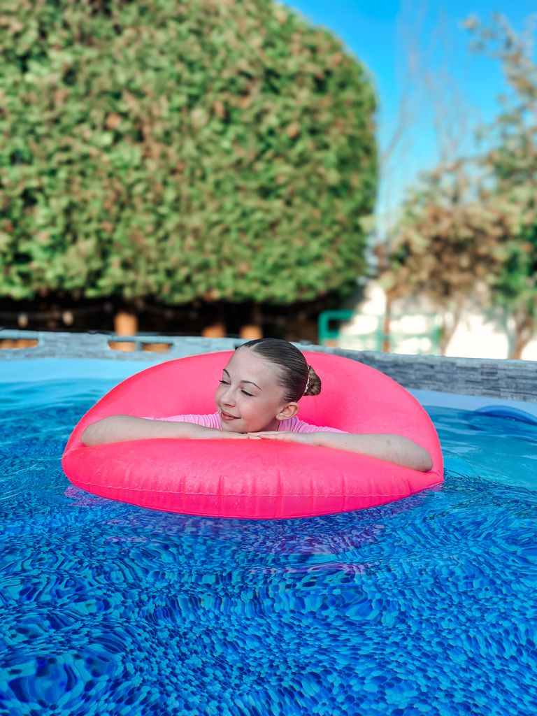 Young girl in a swimming pool in a pink rubber ring 