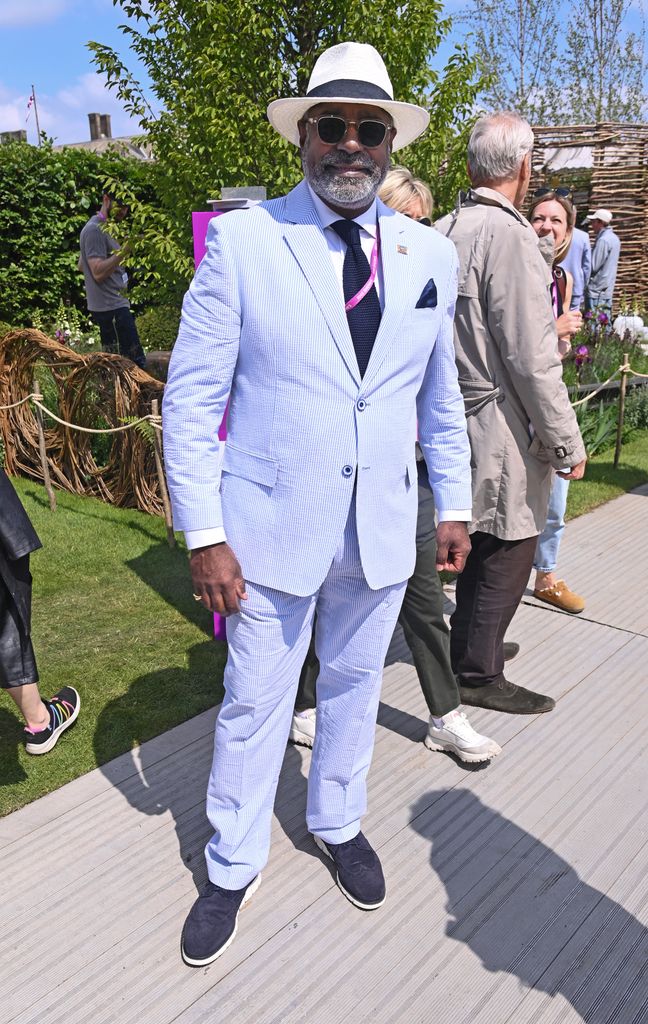 Amar Naher wears a light blue seersucker suit, panama hat, and navy tie at the Chelsea Flower Show 2025