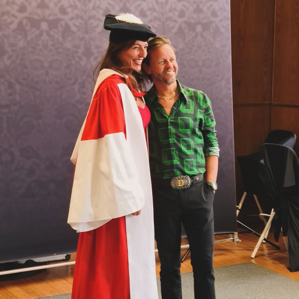 woman posing in doctoral gown alongside partner