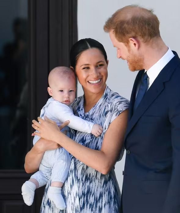 prince harry looking at meghan markle holding archie as a baby