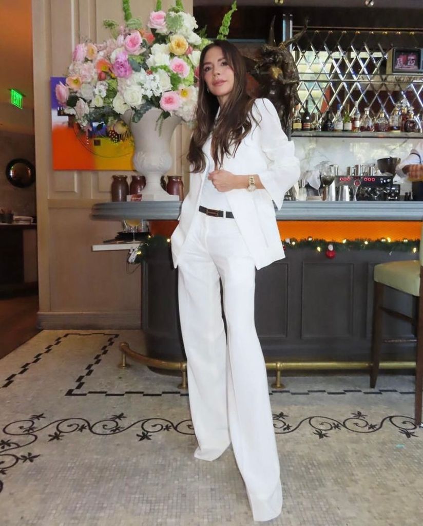 Victoria Beckham wears a white wide-leg trouser suit from her own collection in Decemeber