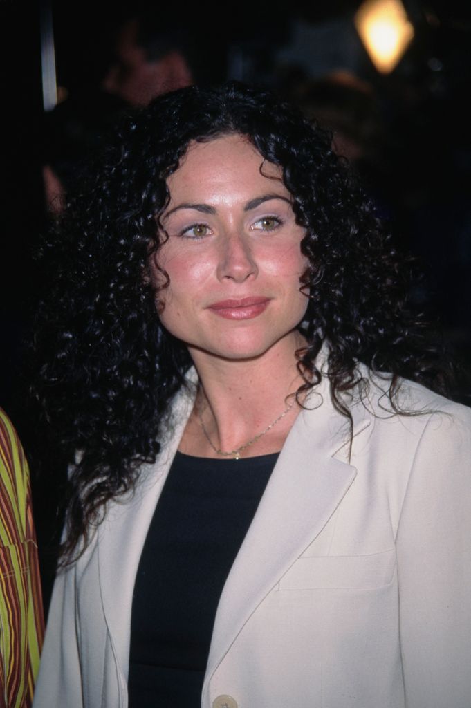 British actress Minnie Driver, wearing a white coat over a black crew neck outfit