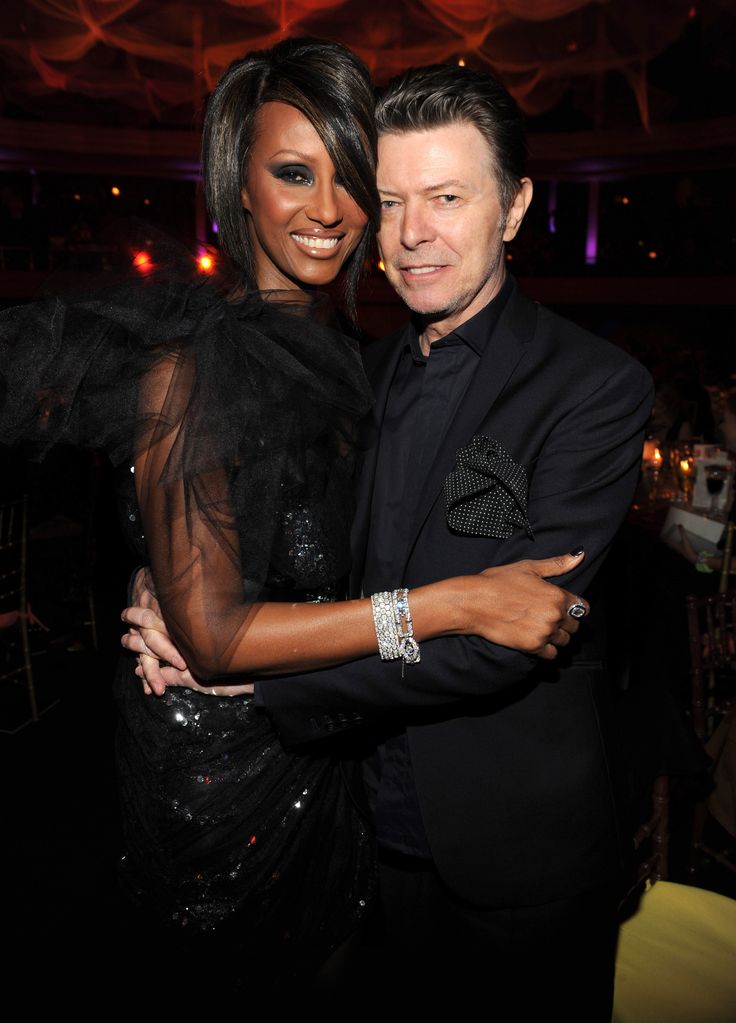 Iman and David Bowie hugging in black outifts