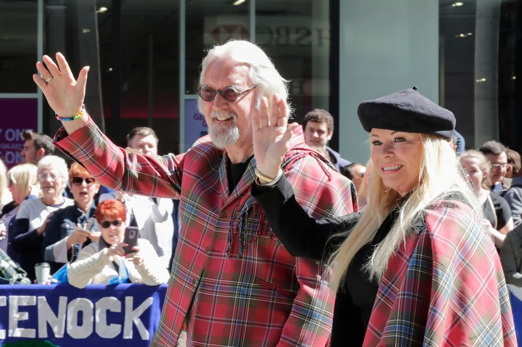 Billy Connolly and Pamela Stephenson waving in tartan