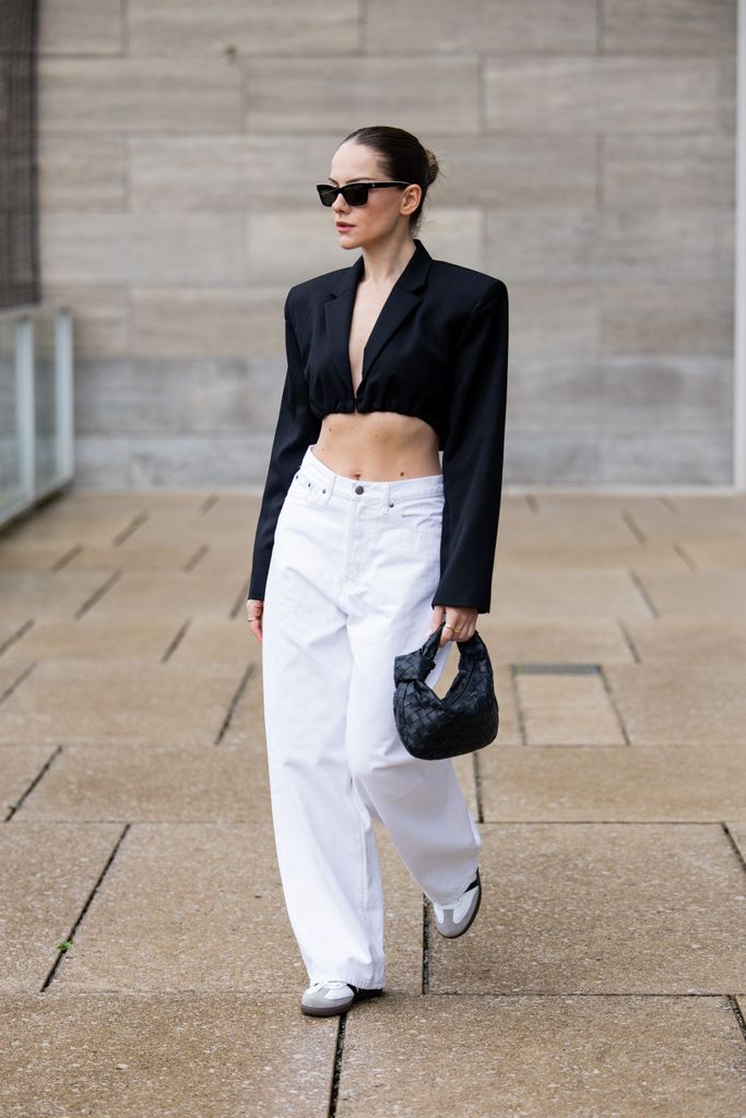  Berna Bilbey wears black bag Bottega Venetta, sunglasses Chanel, black cropped blazer Christopher Esber, white Baggy Jeans Weekday, shoes Adidas Samba during the Berlin Fashion Week SS25 