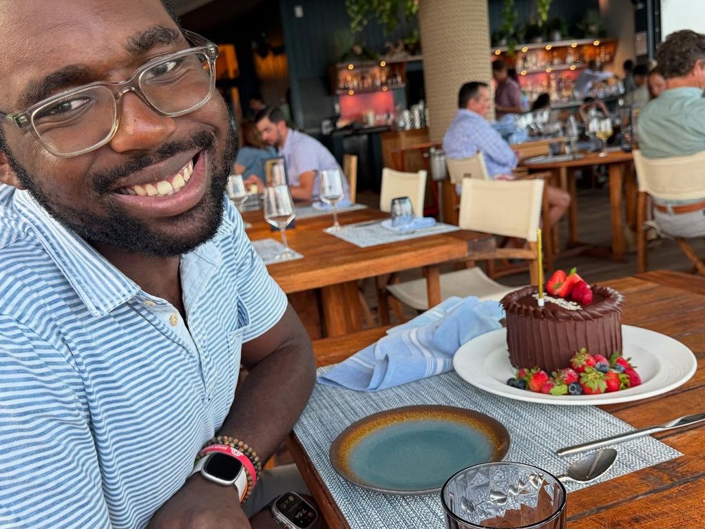 Nick Roker souriant avec un gâteau d'anniversaire sur une table