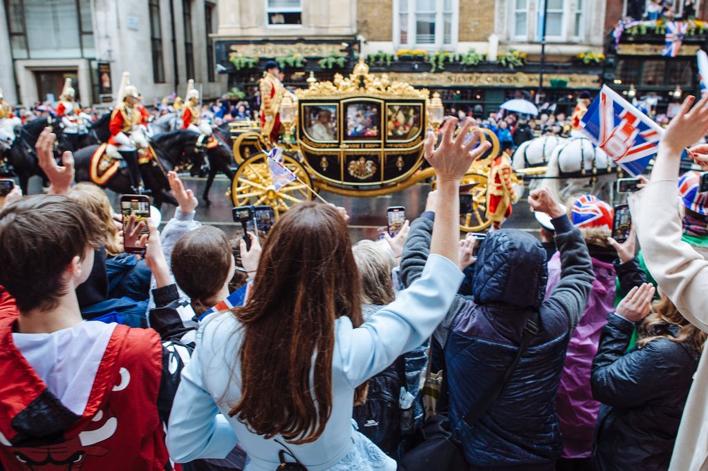 Elizabeth and the crowd waves as the royal carriage passes by