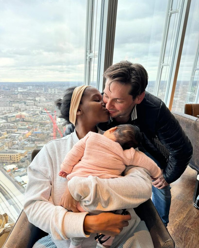 Oti Mabuse kissing husband Marius Iepure while holding baby daughter