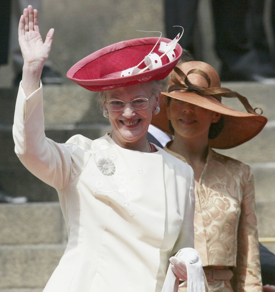 Queen Margrethe waving wearing white outfit and red hat