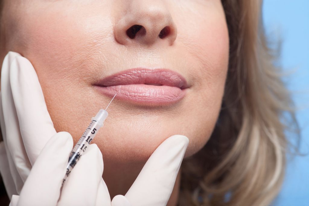 Close up of woman receiving botox injection in lips