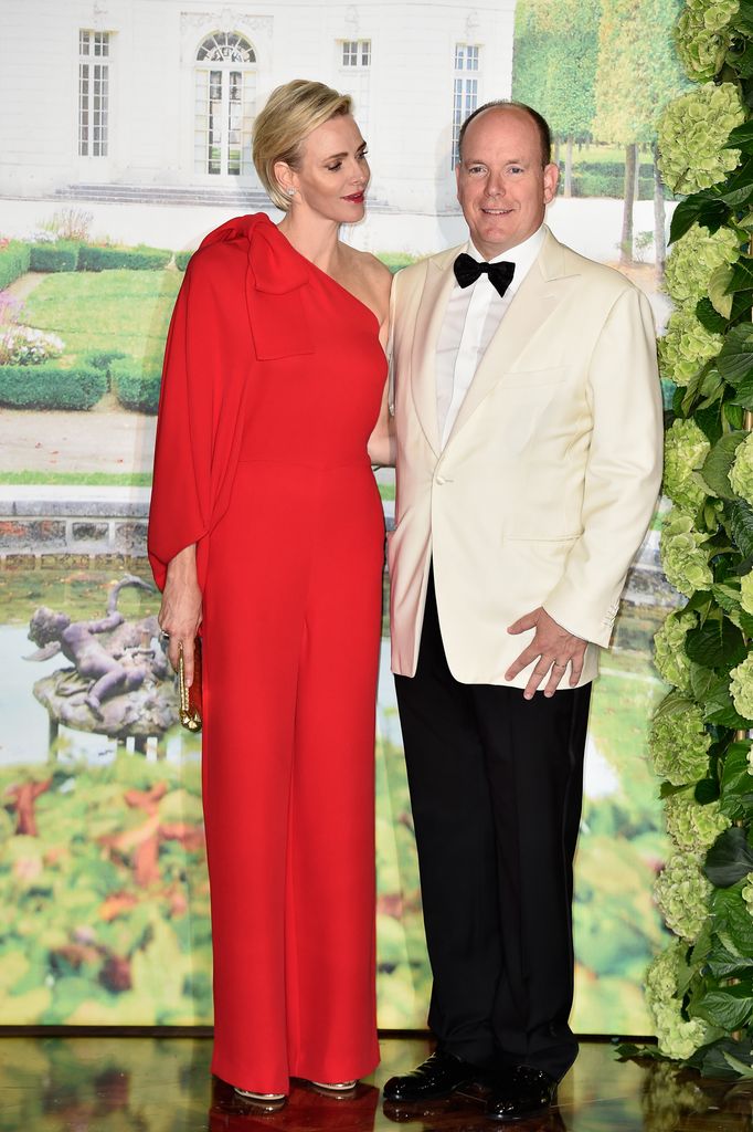 Princess Charlene in a fiery red jumpsuit with Prince Albert